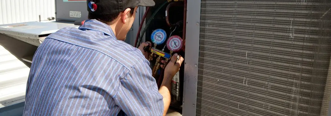 HVAC technician servicing a condenser unit in North Oaks